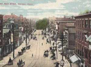 Bird's-eye view postcard of West Main Street in Meriden, Connecticut from a postcard mailed in 1912. All the vehicles on the street are horse-drawn. Trolley tracks can be seen down the middle of the street, which may not be paved.