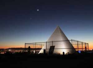 Hunt's Tomb under a waning crescent moon in Papago Park, Phoenix Arizona, with the lights of Phoenix beyond.